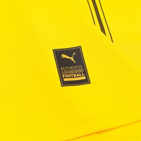 Close-up of a Borussia Dortmund Home Jersey 24/25, featuring a tag with a black label showing a gold puma silhouette and text that reads Authentic Licensed Football. Black diagonal lines accent the bright yellow fabric.
