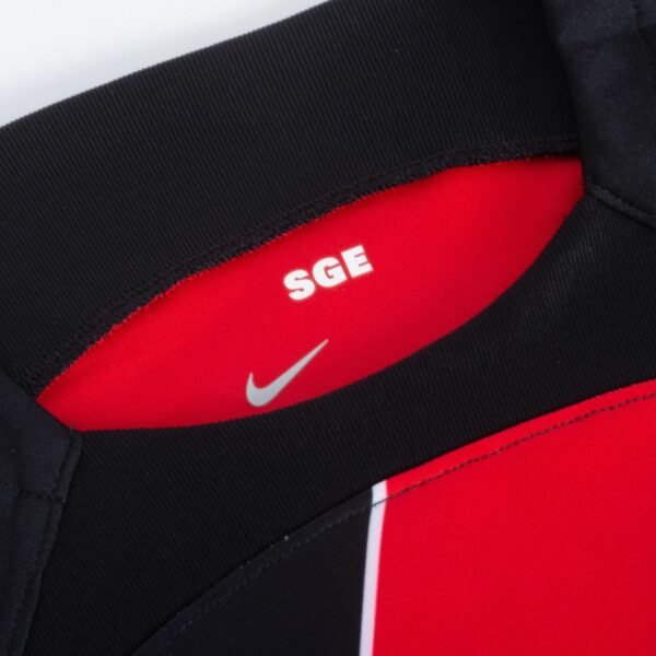 Close-up of the Eintracht Frankfurt Home Jersey 23/24 collar, featuring a sleek black and red blend with a small white SGE text and iconic white Nike swoosh. The vibrant red peeks out from beneath the stylish black outer layer.