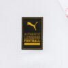 A close-up of a white fabric with a black and gold label, akin to the Leipzig Home Jersey 24/25 - Fan Edition, features a pouncing feline logo and the words AUTHENTIC LICENSED FOOTBALL in uppercase letters.