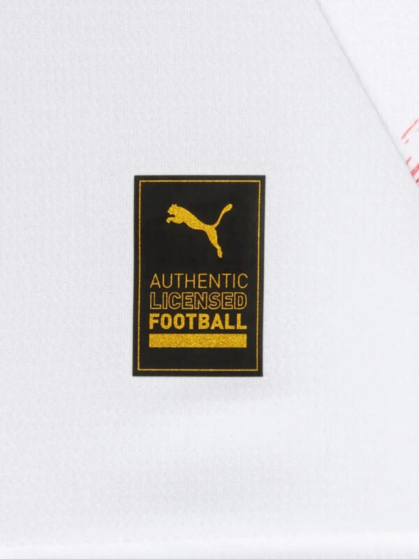 A close-up of a white fabric with a black and gold label, akin to the Leipzig Home Jersey 24/25 - Fan Edition, features a pouncing feline logo and the words AUTHENTIC LICENSED FOOTBALL in uppercase letters.