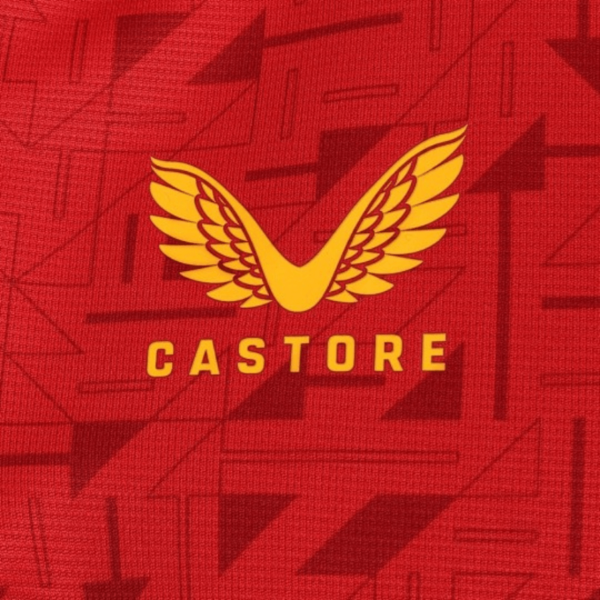 The Wolverhampton Away Jersey 23/24 features a red fabric with geometric patterns and a central logo comprising stylized yellow wings and the word CASTORE in yellow.
