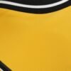 Detailed view of the Wolverhampton Home Jersey 23/24 featuring a yellow fabric with a textured surface and a black and white striped border at the top.