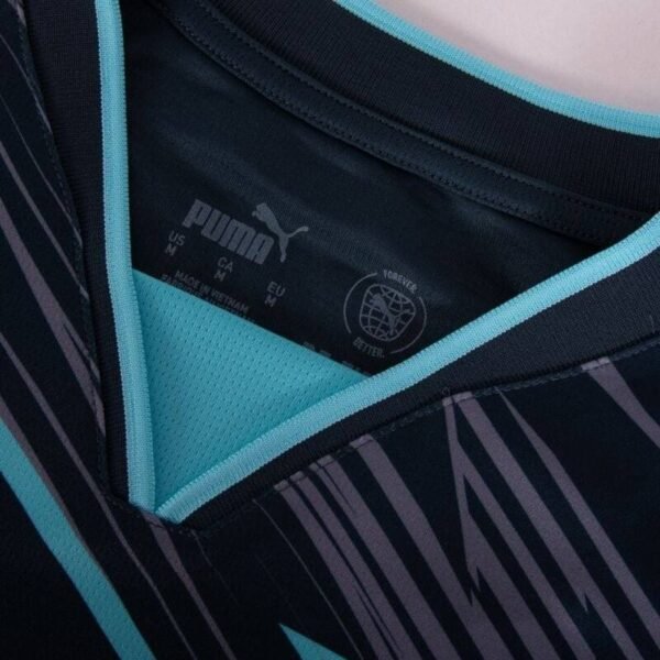 Close-up of a Puma RB Leipzig Third Jersey 24/25. The jersey features a geometric black and teal pattern, showcasing the neckline with visible size and care labels, embodying a modern athletic design.