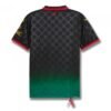 The AC Milan x OFF White Black Jersey 24/25 - Fan Edition features a black and green gradient with subtle cross patterns, red accents on the collar and sleeve edges, and yellow design elements and text on the sleeves for contrast.
